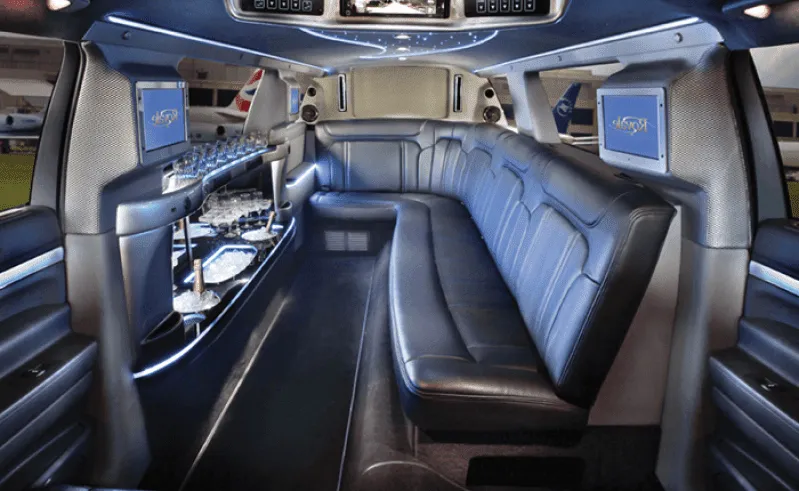 White Ford Excursion Limousine Ford Excursion Limousine interior with sofa-style seating, LED accent lighting and bar area for limo rental