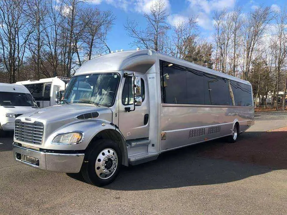 Silver 32 Passenger Limo Bus exterior with tinted windows for party bus rental