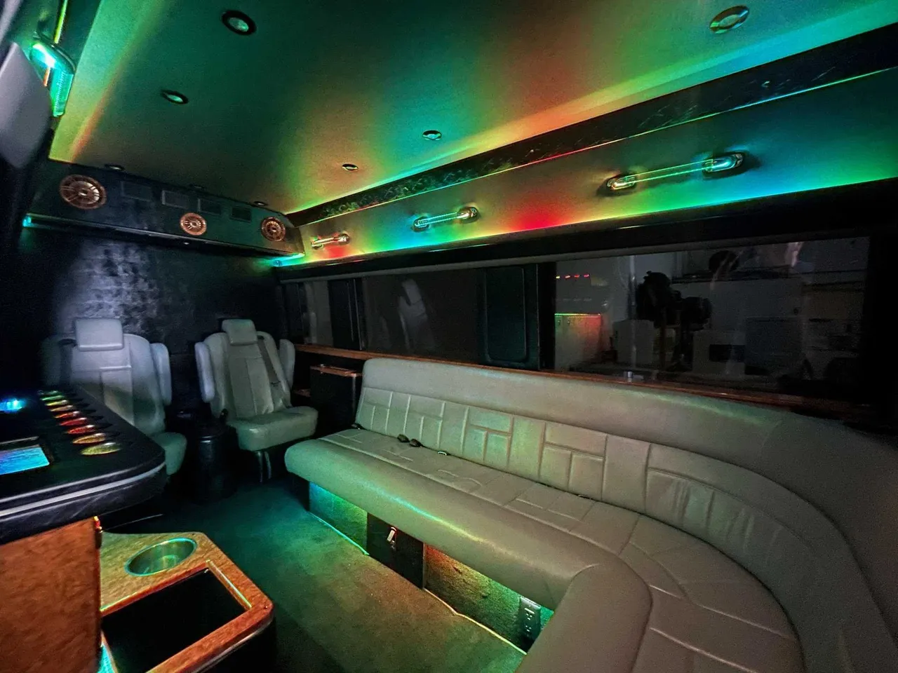 Mercedes Sprinter Limo interior with sofa-style seating, captain's chairs and LED accent lighting for party bus rental