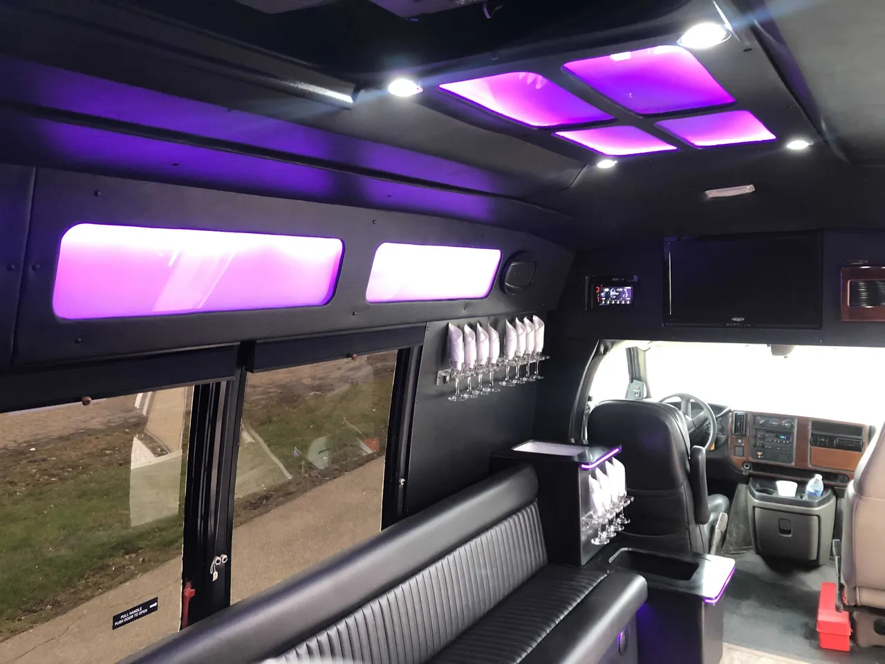 Small party bus interior with perimeter lounge seating, LED ceiling lighting and glassware holders for party bus rental Small party bus interior with perimeter lounge seating, LED ceiling lighting and glassware holders for party bus rental