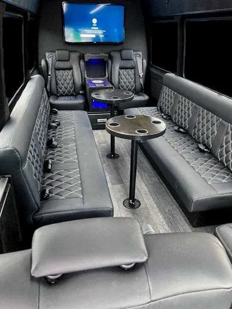 12 Passenger Mercedes-Benz Party Bus interior shot — captain's chairs, passenger tables and TV screens